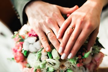Beautiful young wedding couple posing with bouquet of flowers in hands